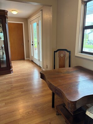 A room with a wooden dining table, a chair, a wooden door, and a window. - Relaxing Punta Gorda Getaway 3BR, Kayaks, Outdoor Oasis (Punta Gorda)