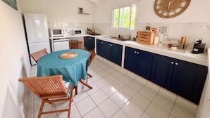 Uma cozinha com mesa, cadeiras, geladeira, micro-ondas, pia e armários.
