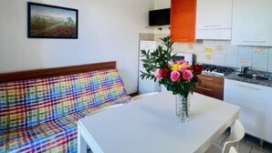A small kitchenette with a dining table and chairs, a sofa, and a TV. - Flat Near the Beach With Terraces (San Michele al Tagliamento)