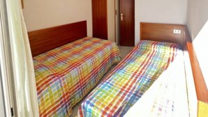 A room with two beds, a wardrobe, and a ceiling light. - Flat Near the Beach With Terraces (San Michele al Tagliamento)