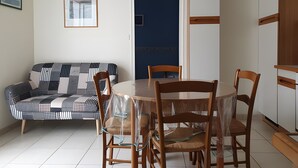 A dining area with a round table, chairs, a sofa, and a door. - Central house in quiet alley (La Tranche-sur-Mer)