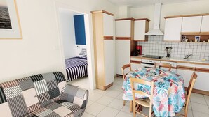 A compact kitchen with white cabinets, a microwave, and a dining table with chairs. - Central house in quiet alley (La Tranche-sur-Mer)