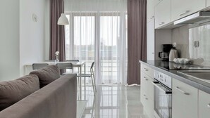 Eine moderne Küche mit Edelstahlgeräten, ein Essbereich mit Tisch und Stühlen sowie ein großes Fenster mit Vorhängen.