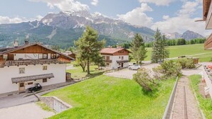 A mountain-view property with wooden buildings, a paved driveway, and a small parking area. - Casa Verocai - Mountain View Terrace (Cortina d'Ampezzo)