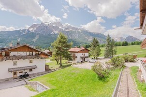 A mountain-view property with wooden buildings, a paved driveway, and a small parking area.