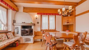 A cozy living room with a fireplace, wooden furniture, and a dining area. - Casa Verocai - Mountain View Terrace (Cortina d'Ampezzo)