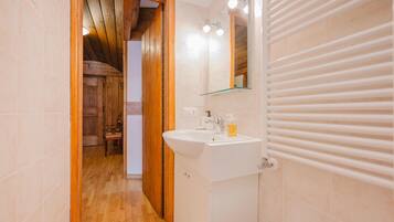 A bathroom with a wooden door, a white sink, a mirror, and a towel rack.