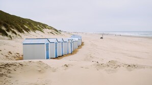 A row of beachside beach huts with a sandy beach and ocean in the background. - Den Burg Holiday Home for 8 (Den Burg)