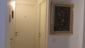 A hallway with two doors, one labeled '1' and the other '2', and a framed painting on the wall. - Perry Guest House (Rome)