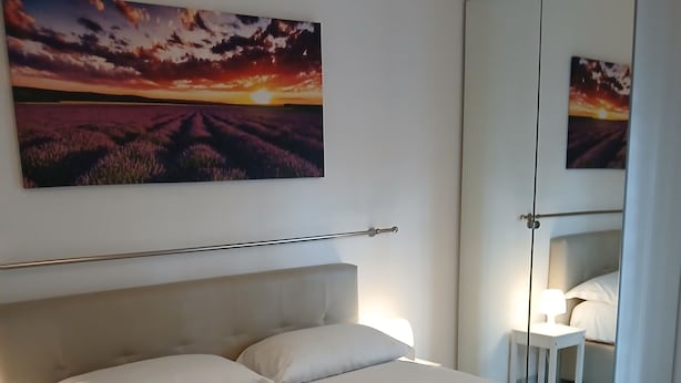 A neatly made bed with white linens and towels, a headboard, and a bedside table with a lamp. - Perry Guest House (Rome)