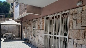A tiled patio area with a covered seating area, a stone wall, and a metal gate. - Perry Guest House (Rome)
