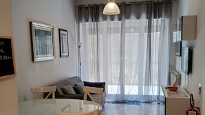 A modern living room with a dining table, chairs, a sofa, a TV, and a fireplace. - Perry Guest House (Rome)