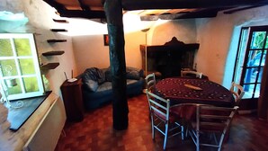 Una habitación acogedora con techo de madera, una mesa redonda con sillas, un sofá azul y una ventana con vistas.