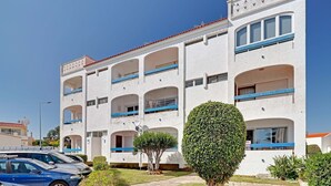 Un edificio de varios pisos con balcones, cielo despejado y césped bien cuidado.