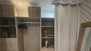 A room with a wooden wardrobe, a small shelf with a bust, and a curtain. - Leonard's (Bièvres)