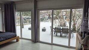 A modern bedroom with a large sliding glass door leading to a snowy outdoor area. - Leonard's (Bièvres)