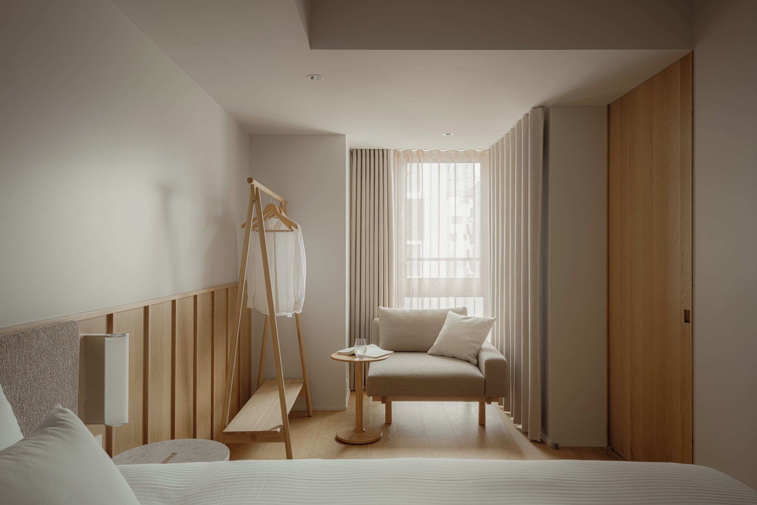 Una habitación de hotel moderna con una cama, una zona de estar, una mesita y un armario.