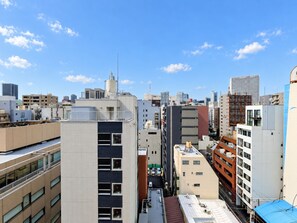 A cityscape with modern buildings, including a prominent building with a unique facade and a clear blue sky. - TOMI. Ginza (Tokyo)