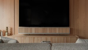 A flat-screen TV mounted on a wooden wall with a built-in speaker below it. - TOMI. Ginza (Tokyo)