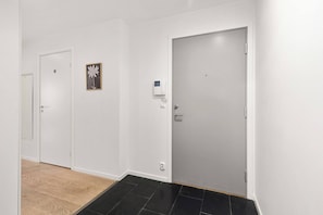 A hallway with two white doors, a small framed picture, and a thermostat on the wall. - Urban Escape - Only Steps From the Waterfront (Oslo)