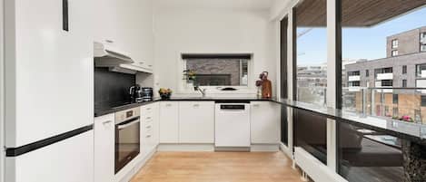 A modern kitchen with white cabinets, a black countertop, and a window overlooking a cityscape.