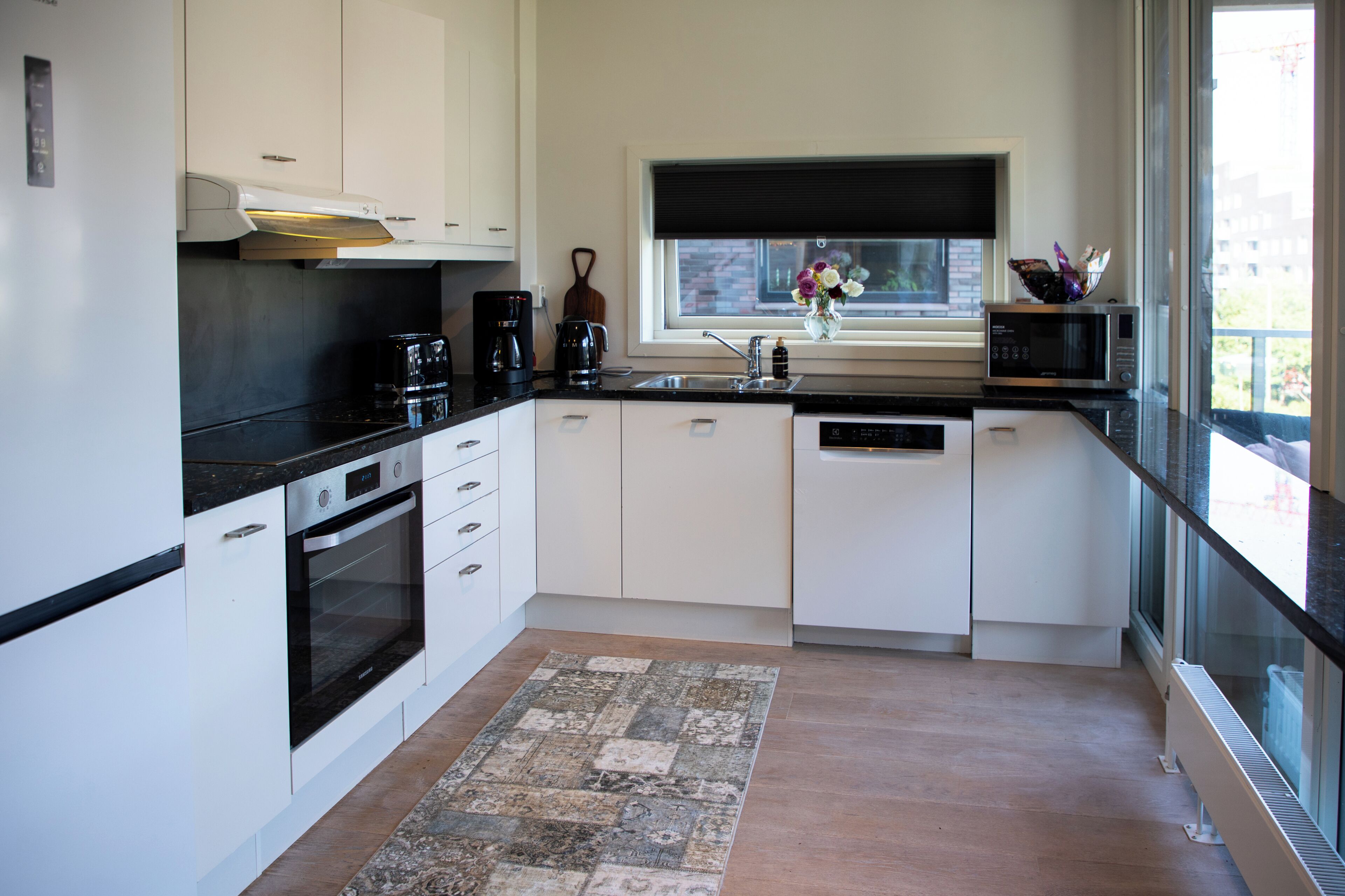 A modern kitchen with white cabinetry, a built-in oven, a coffee maker, and a microwave.