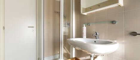 A bathroom with a shower, sink, and mirror.