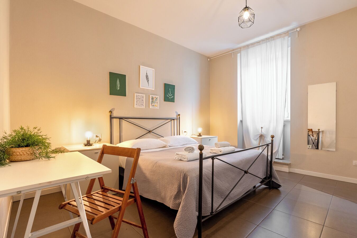 A neatly arranged bedroom with a bed, bedside table, chair, and a desk.