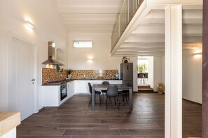 Una cucina moderna con zona pranzo, pavimento in legno e vista all'esterno.