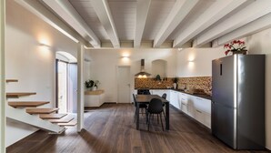 Una cocina moderna con piso de madera, comedor y refrigerador de acero inoxidable.