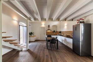 Una cocina moderna con piso de madera, comedor y refrigerador de acero inoxidable.