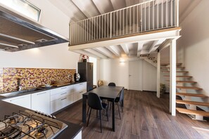 Una cucina moderna con zona pranzo, una scala in legno e un pannello decorativo.