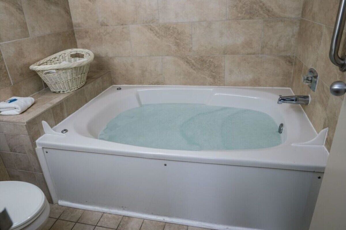 A bathroom with a bathtub, a toilet, and a wicker basket on the wall.