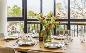 A dining table set with plates, cutlery, and wine glasses, with a vase of flowers in the center. - Spacious 3BR Retreat Overlooking Marina (Msida)