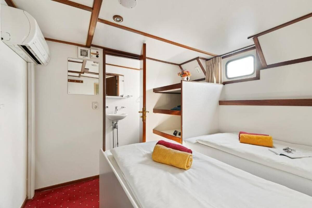 A compact cabin with two beds, a small window, a mirror, a sink, and a wardrobe.