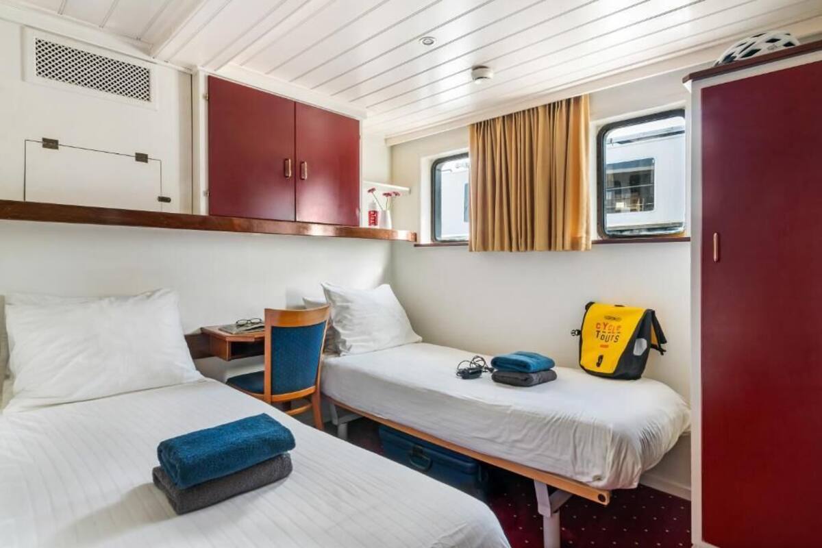 A cabin with two beds, a wardrobe, a small table, and a window with curtains.
