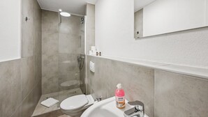 Un baño moderno con ducha, inodoro, lavabo y espejo.