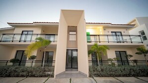 A modern building with a central entrance, balconies, and a green wall. - COZY APT 10 AIRPORT (Punta Cana)