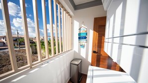 A balcony with a view of buildings and a trash bin. - COZY APT 10 AIRPORT (Punta Cana)