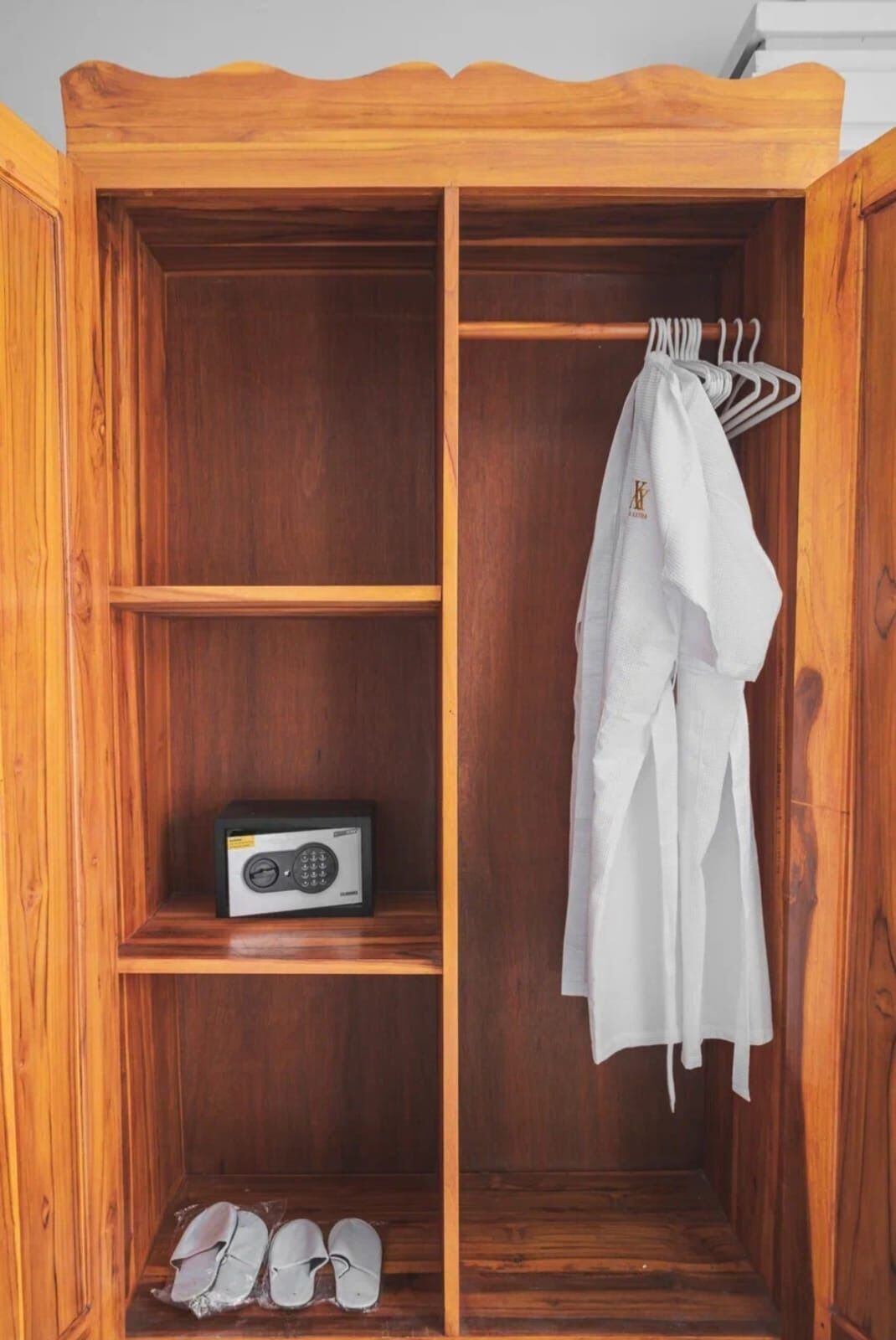 Une armoire en bois avec une radio, une paire de chaussures et un vêtement blanc suspendu à l’intérieur.