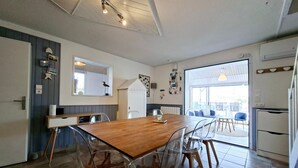 A modern kitchen with a wooden dining table, clear chairs, and a large window. - Holiday Home "La Maison De Marion" with Private Terrace, Wi-Fi, and Air Conditioning (La Tranche-sur-Mer)
