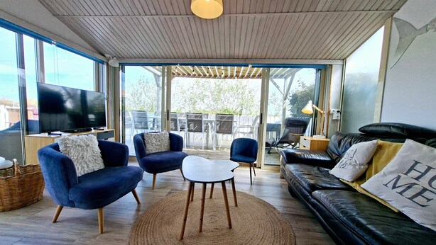 A modern living room with a TV, sofas, chairs, and a large window. - Holiday Home "La Maison De Marion" with Private Terrace, Wi-Fi, and Air Conditioning (La Tranche-sur-Mer)