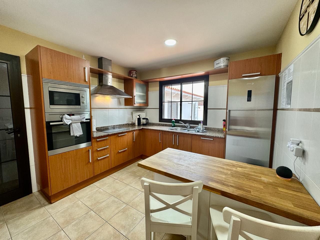 A kitchen with wooden cabinets, a stainless steel oven, a refrigerator, and a window.