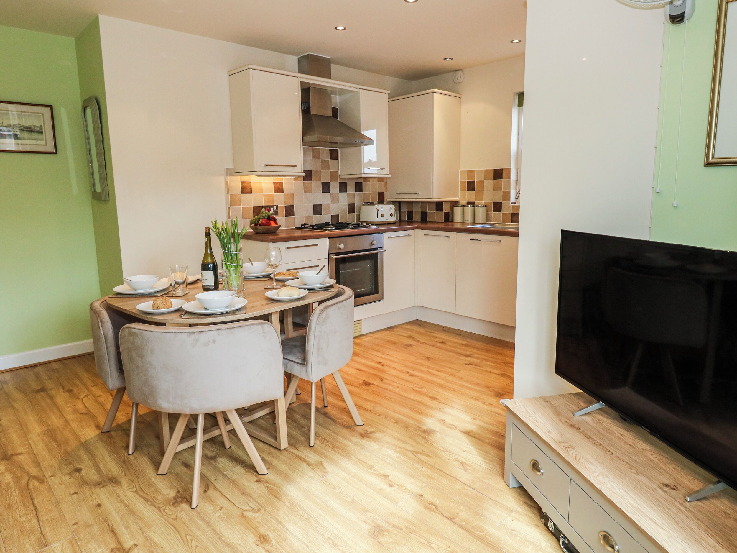 A compact kitchen with a dining area, a TV, and a wooden cabinet.