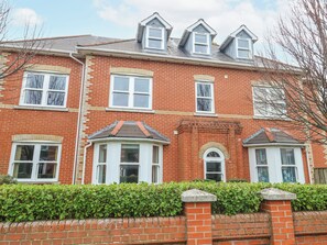 A red brick house with multiple windows, a bay window, and a small porch. - Rodwell Holt (Weymouth)