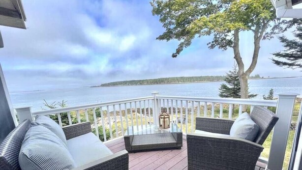 A deck with wicker furniture and a view of the water. - CASTLEWOOD COTTAGE - Town of Owls Head (Owls Head)