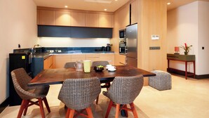 Una cocina moderna con comedor, armarios de madera, refrigerador, microondas, horno y una pequeña mesa con sillas.