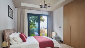 Un dormitorio con cama, mesita de noche, lámpara, un amplio ventanal con cortinas y vistas al exterior.