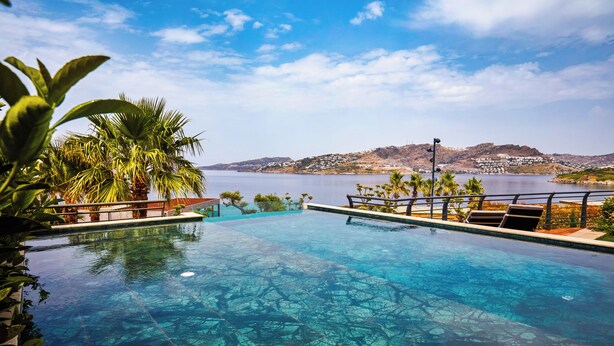 Piscina cristalina con vistas a una colina distante y una masa de agua.