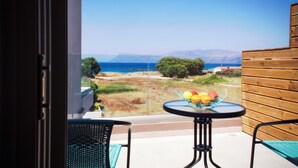 Un balcon avec une table dressée pour le petit-déjeuner, offrant une vue sur un paysage côtier avec des arbres et des montagnes.
